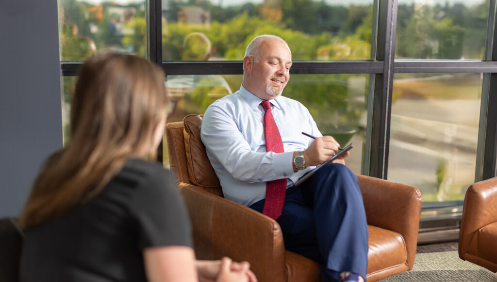 small meeting between two Elite Income Advisors employees with the male employee sitting on a brown leather chair