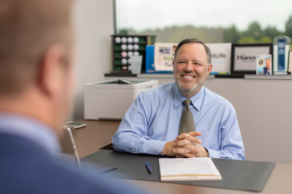 Elite Income Advisor financial advisor sitting behind desk meeting with a client