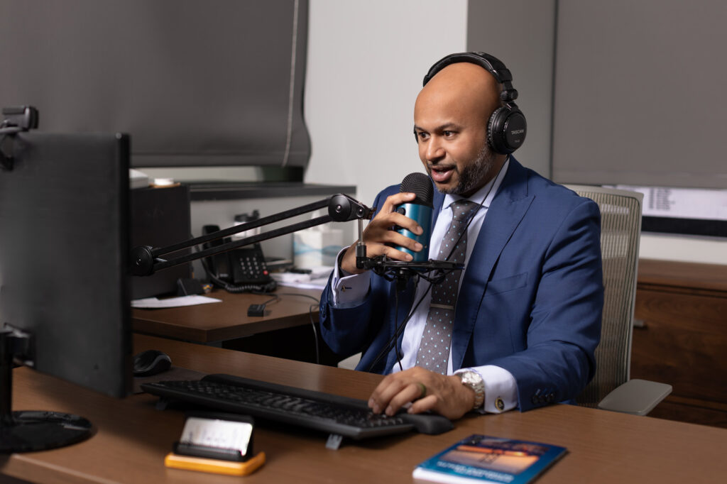 Elite Income Advisors employee speaking into a large microphone behind his desk