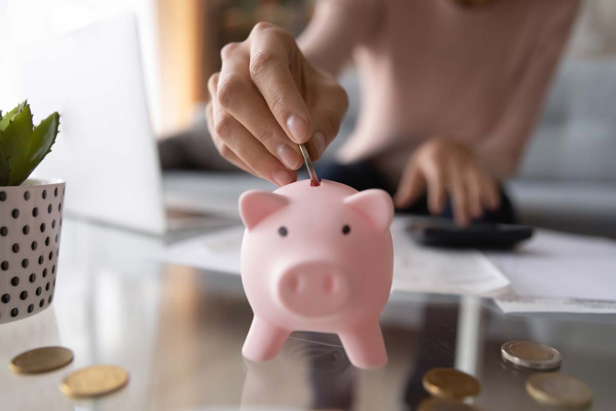 Young woman adding a coin to a piggy bank