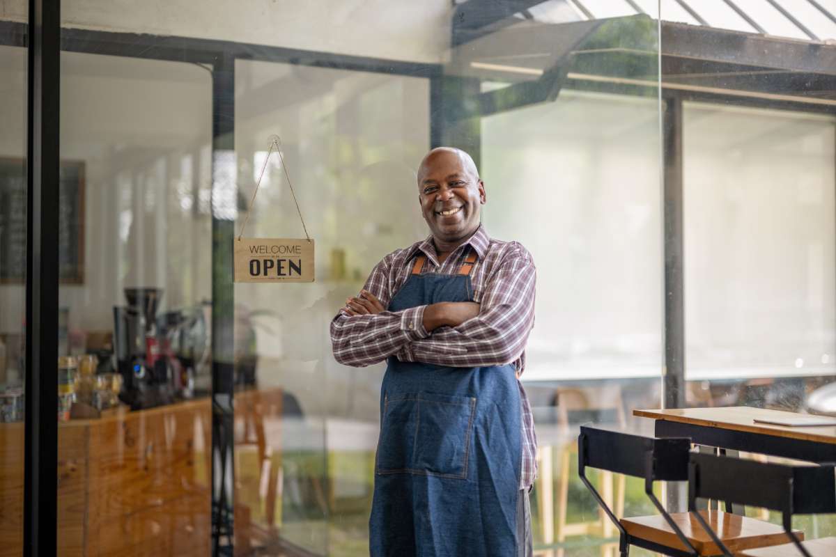 Smiling business owner standing in front of his store