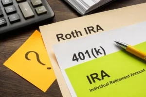 Sheets of colorful paper reading Roth IRA, 401(k), and IRA on a desktop.