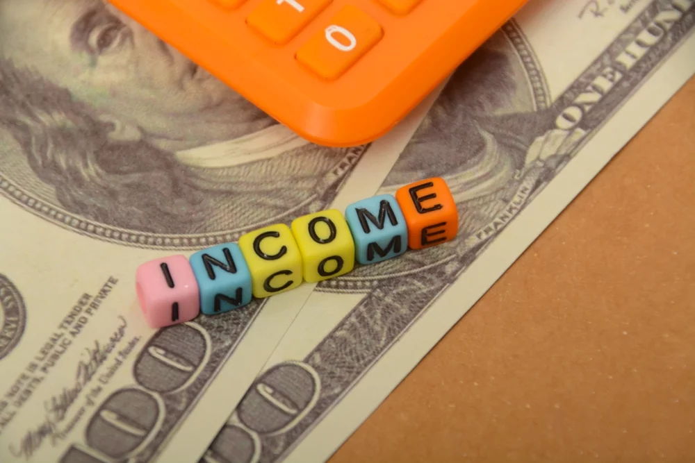 Qualified vs. non-qualified annuity concept shown with income letter beads on cash beside a calculator for retirement planning