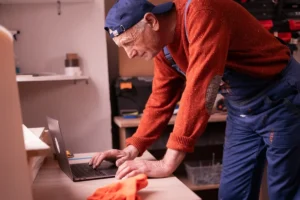 Older self-employed professional in work clothes reviewing self-employment retirement funds on a laptop.