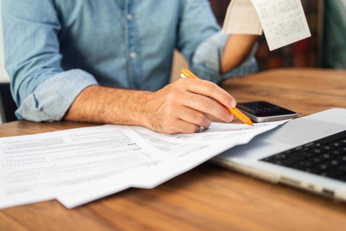 Cropped image of man in denim shirt filing taxes