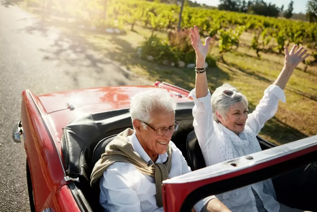 Retired couple smiling in a convertible